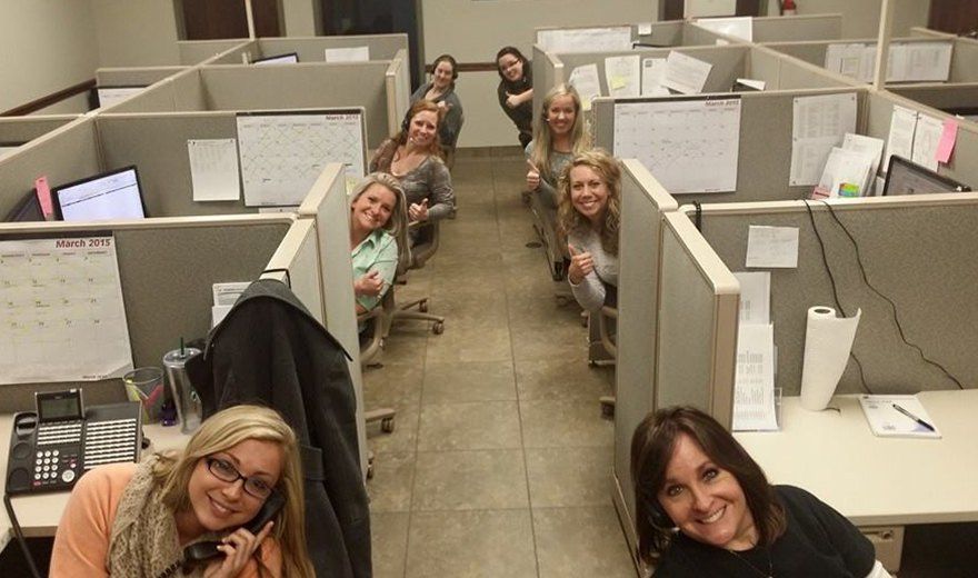 Team members smiling in cubicles