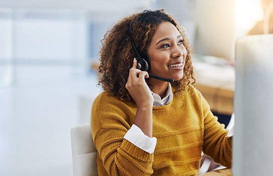 smiling dental administrator with a headset and computer