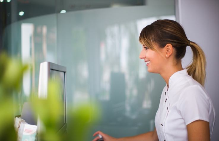 Friendly dental team member behind reception desk