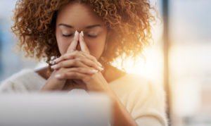 A woman with her hands folded against her face.