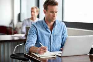 Man on laptop taking notes