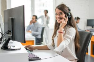 A woman on the phone while on a computer.