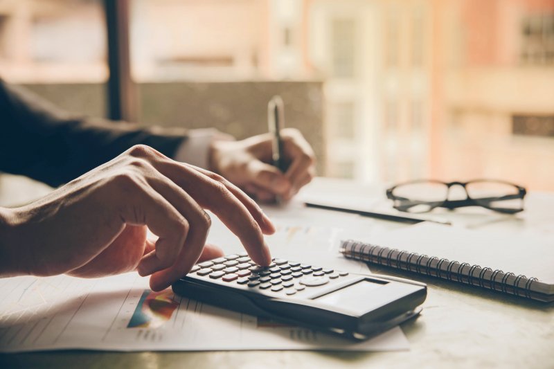 A person writing and using a calculator.