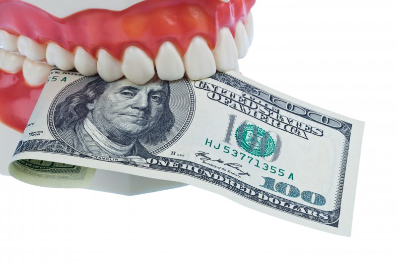 A denture mold holding a $100 bill.