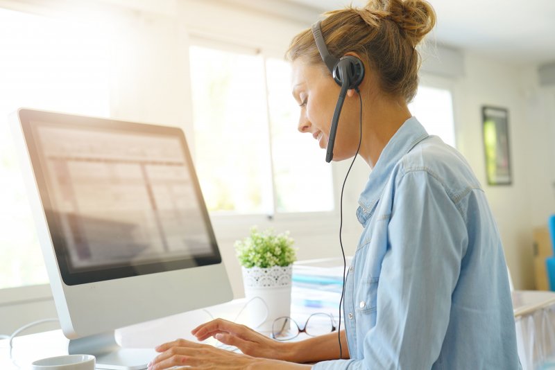 A woman speaking on the phone via a headset.