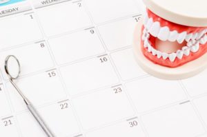 teeth and dental tool on calendar for patient scheduling