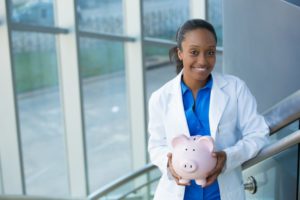 dentist holding a piggy bank getting help with dental insurance verification