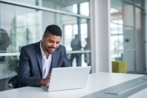 man smiling and working on a computer with dental software