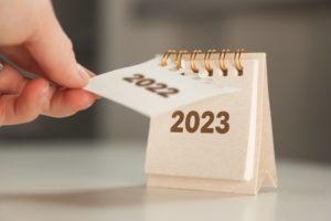hand turning the calendar from 2022 to 2023