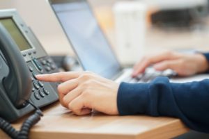 person typing into office phone to listen to messages