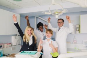 dental team raising their hands and celebrating