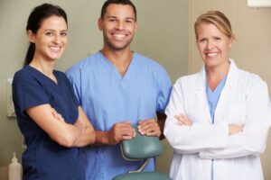 dentist, hygienist, and front desk team member smiling and standing together