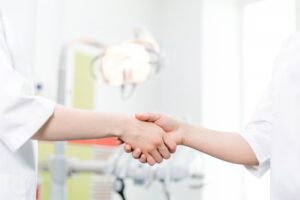 two hands shaking in a dental office