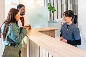 happy front desk employee talking to patients