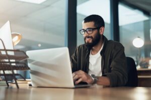 man smiling and working on a laptop