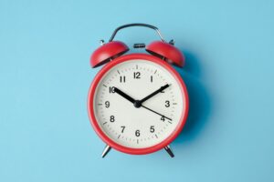 red alarm clock with light blue background